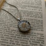 Pressed white daisy flower pendant necklace on open vintage book